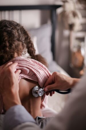 doctor examining a child with a stethoscope on their back